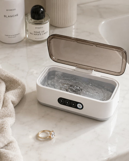 Aurelle Sparkle Bath ultrasonic jewelry cleaner open on a marble vanity with a diamond ring beside it